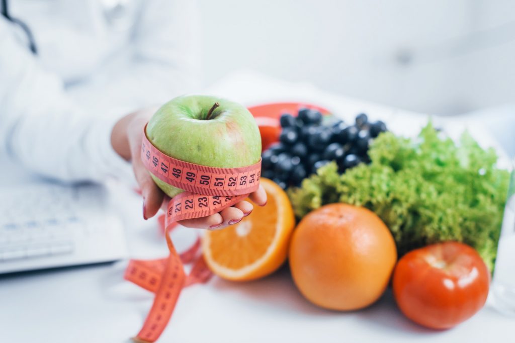 Female nutritionist in white coat sitting indoors in the office at workplace